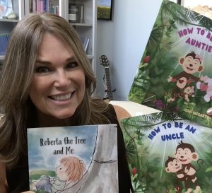 Author Jean McCarthy holding three books she has written for children, Roberta the Tree and Me, How to be an Uncle and How to be an Auntie